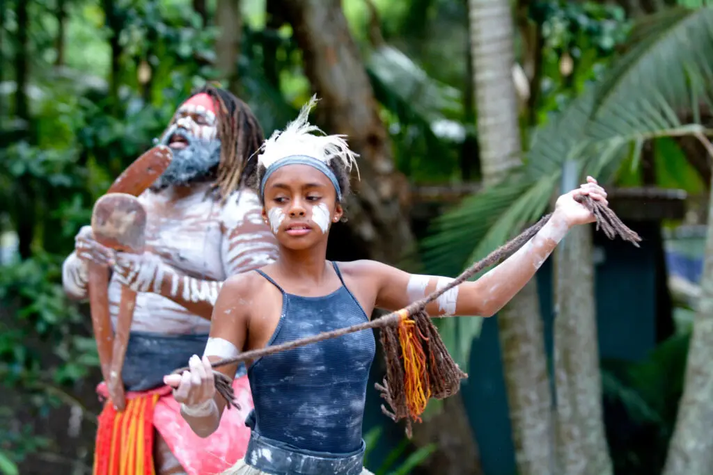 Young adult Indigenous Australian Aboriginal woman dancing to the singing rhythm sound of Australian Aboriginal adult man in the tropical far north of Queensland, Australia.