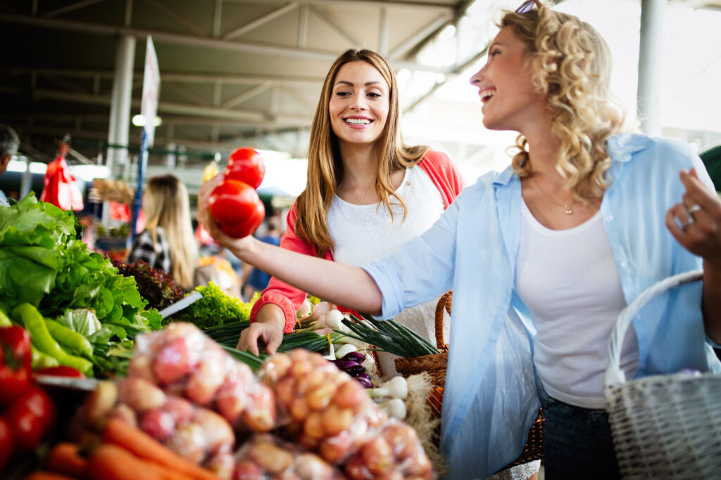 Young happy women shopping vegetables and fruits on the market. Darwin Visitor Guide