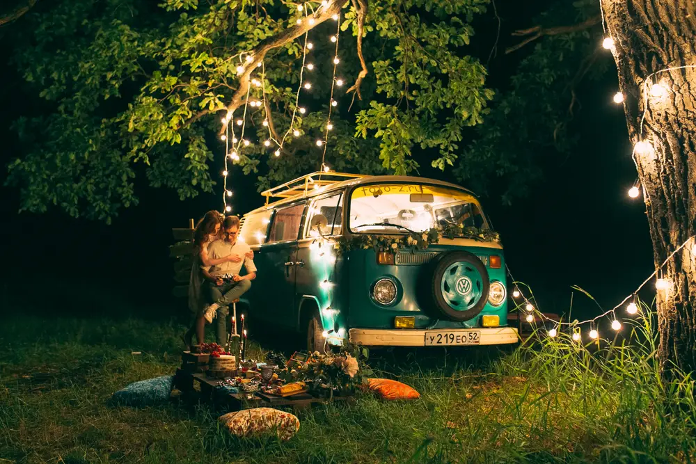 Carcoar Dam Camping Area. Night picnic of a young couple near a green bus.