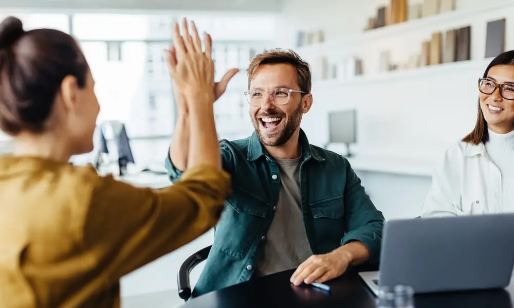 Trippie pricing. Successful business people giving each other a high five in a meeting. Two young business professionals celebrating teamwork in an office. Trippie