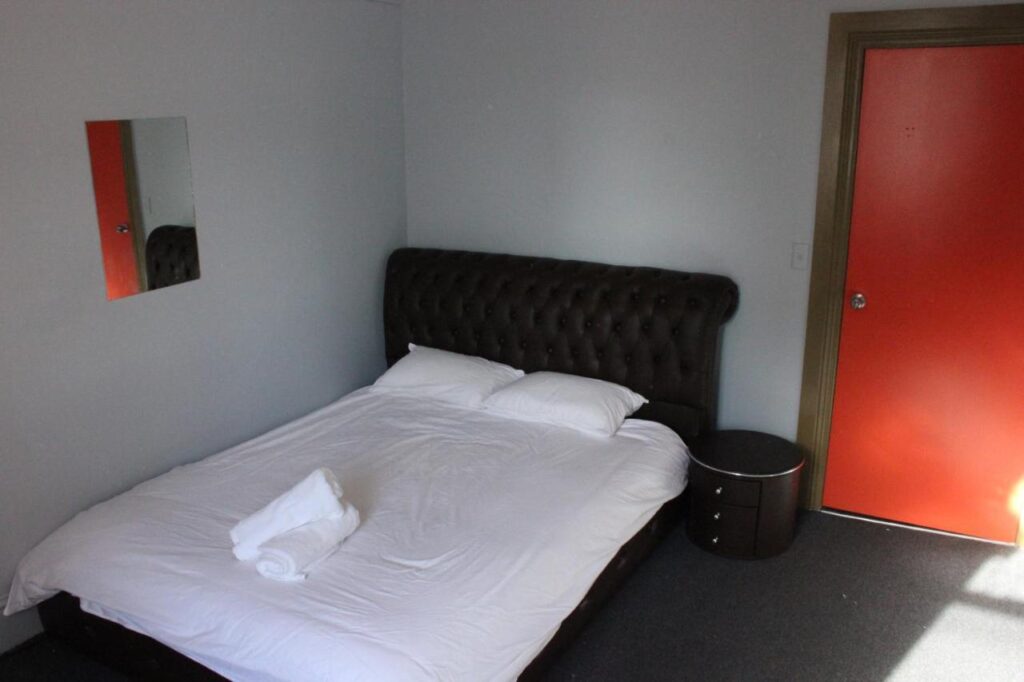 A queensized bed with clean sheets in a private room at Backpackers Imperial Hotel