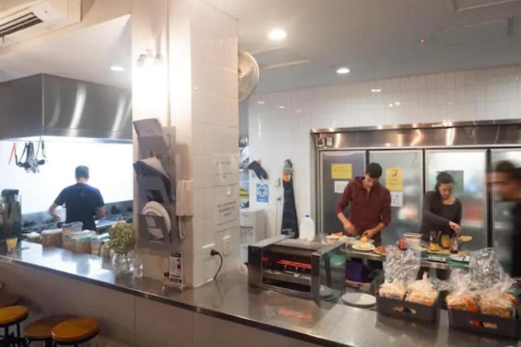 Travellers making breakfast, lunch and dinner in a fully equiped stainless steel benched kitchen at Big Backpackers Hostel