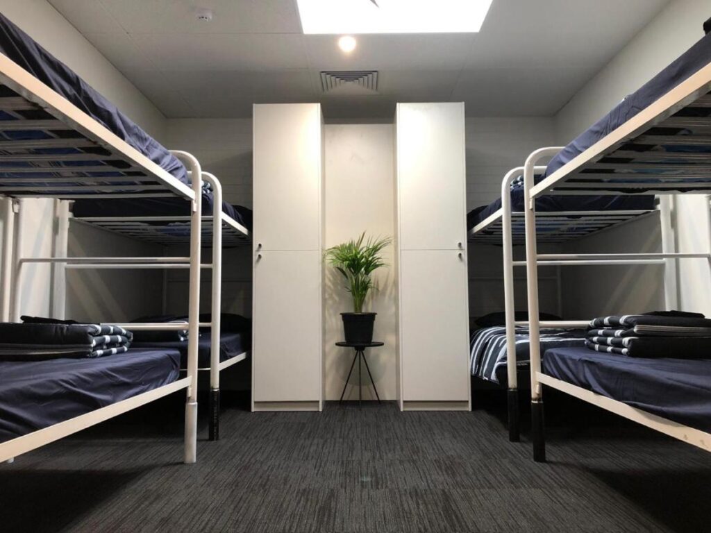 An eight bed dormitory with storage and a pot plant in the middle of the room at Spinners Backpackers