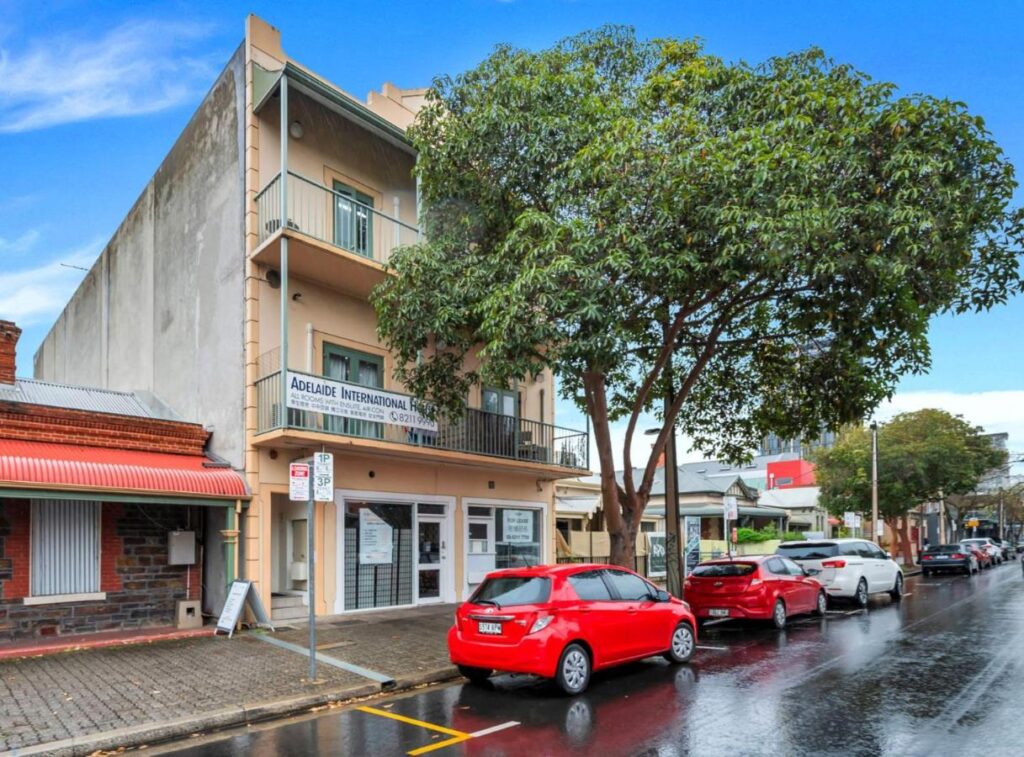 A street view with trees and red cars at the front of Studio 26 Wright Lodge