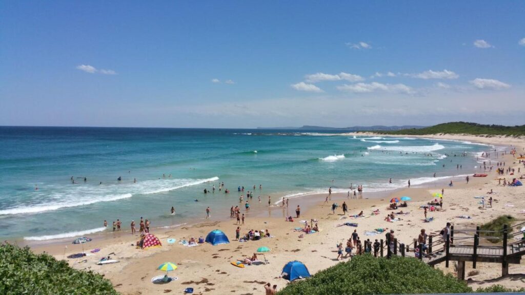 Roberts Beach with visitors swimming and sun bathing near The Entrance Backpackers