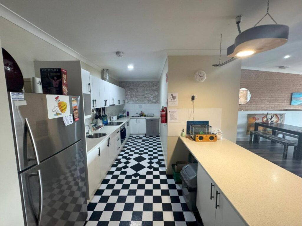 A clean well maintained kitchen with refrigerator wooden benchtops and facilities of travellers and guests to cook breakfast, lunch and dinners at The Entrance Backpackers 