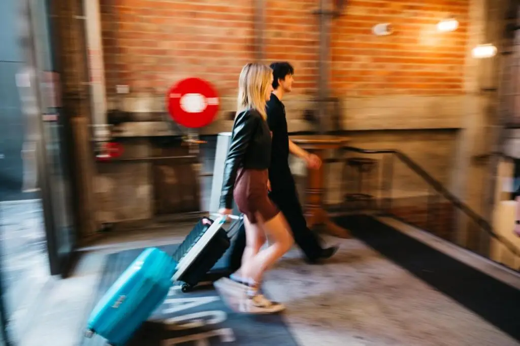 A couple of travellers walking toward a star case while carrying their luggage at The Lansdowne Hotel