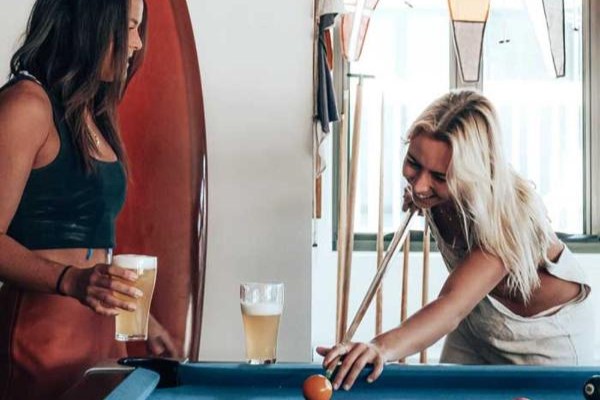 Travellers socialising while playing a game of pool at The Surf House Byron Bay