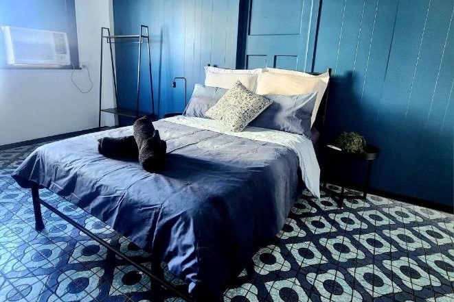 Modern private room with blue feature wall behind and blue bed covers at Wanna Stay Hostel