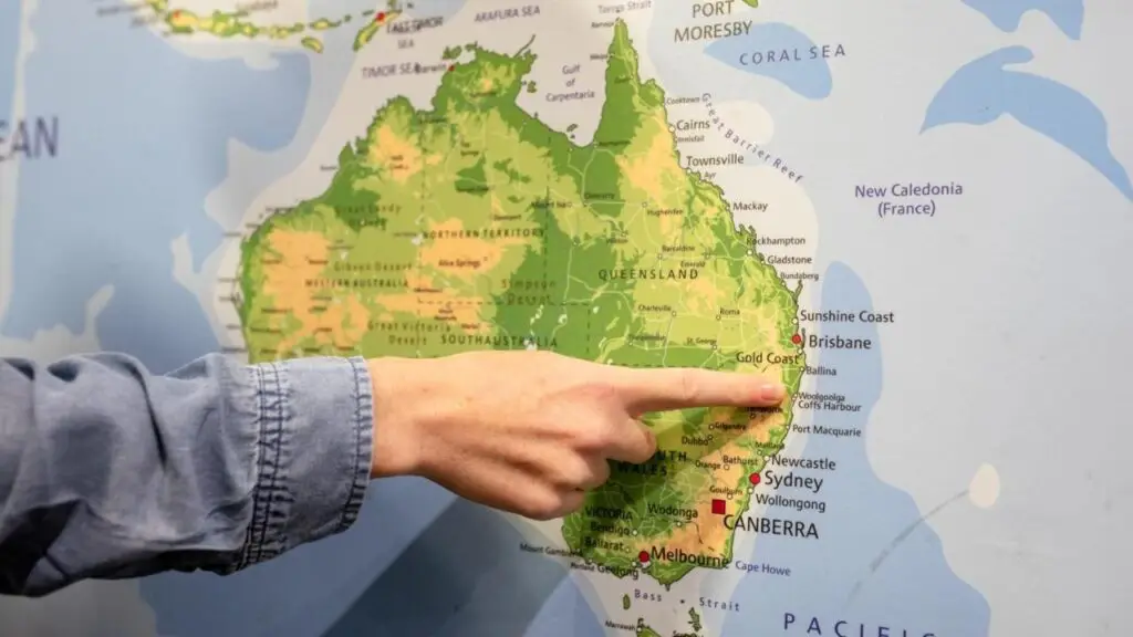 A map of Australia and a guest pointing at the location of Woolgoolga where Woppi Backpackers is located.