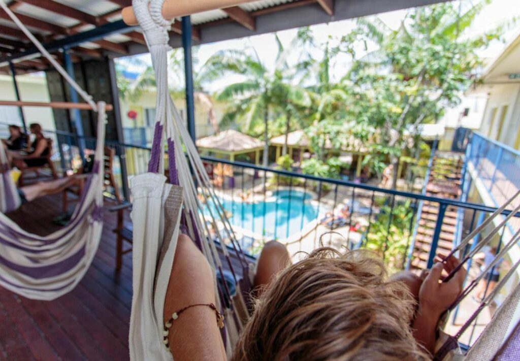 Traveller relaxing in a hammock on the deck overlooking the swimming pool at YHA Cairns Central