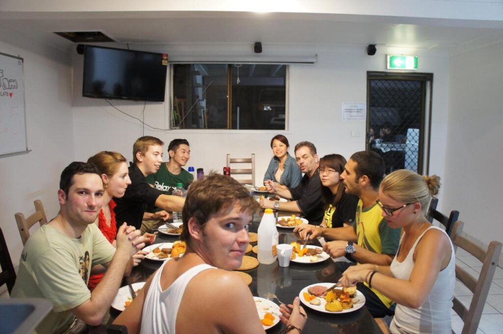 A bunch of travellers and guests having dinner together and socialising at Gonow Family Backpackers Hostel