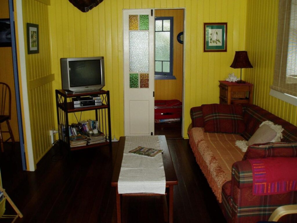 The lounge room with a cosy couch, Television and coffee table at Mango Tourist Hostel
