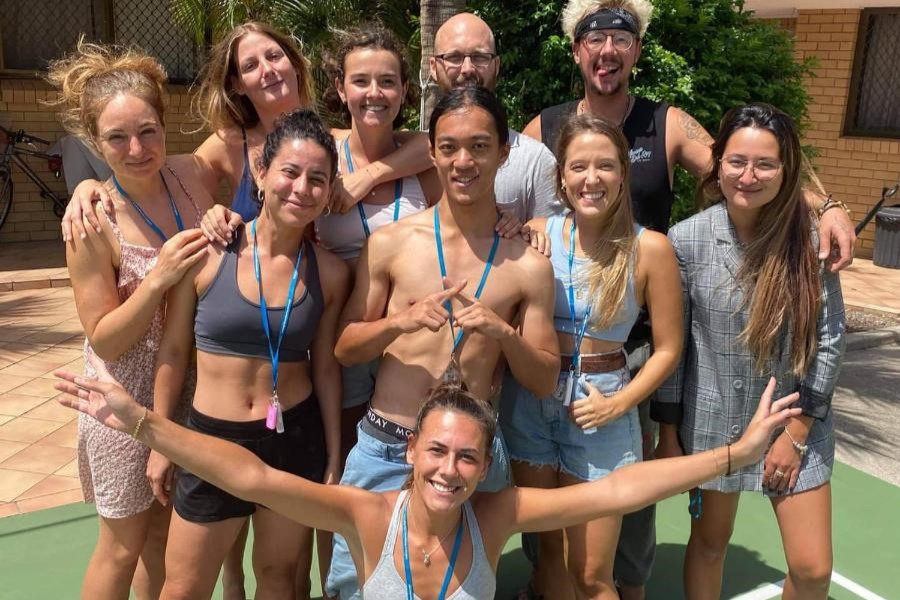 A bunch of travellers posing for a photo on the volleyball court at Maxmee Backpackers Resort