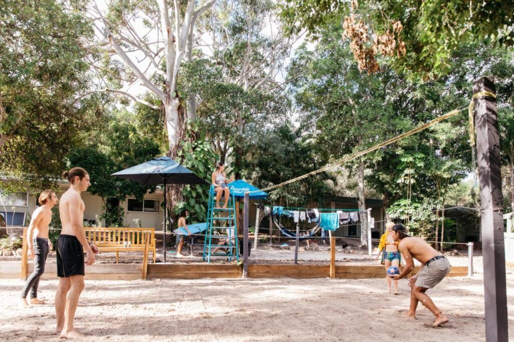 Travellers and backpackers playing a friendly game of beach volleyball at Nomads Noosa