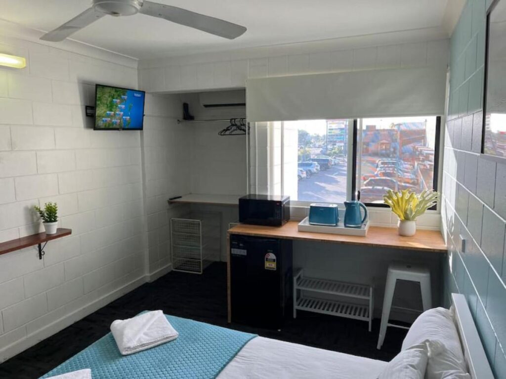 Private room with television, refrigerator, desk and a large window at Seaside Lodge Hostel Townsville