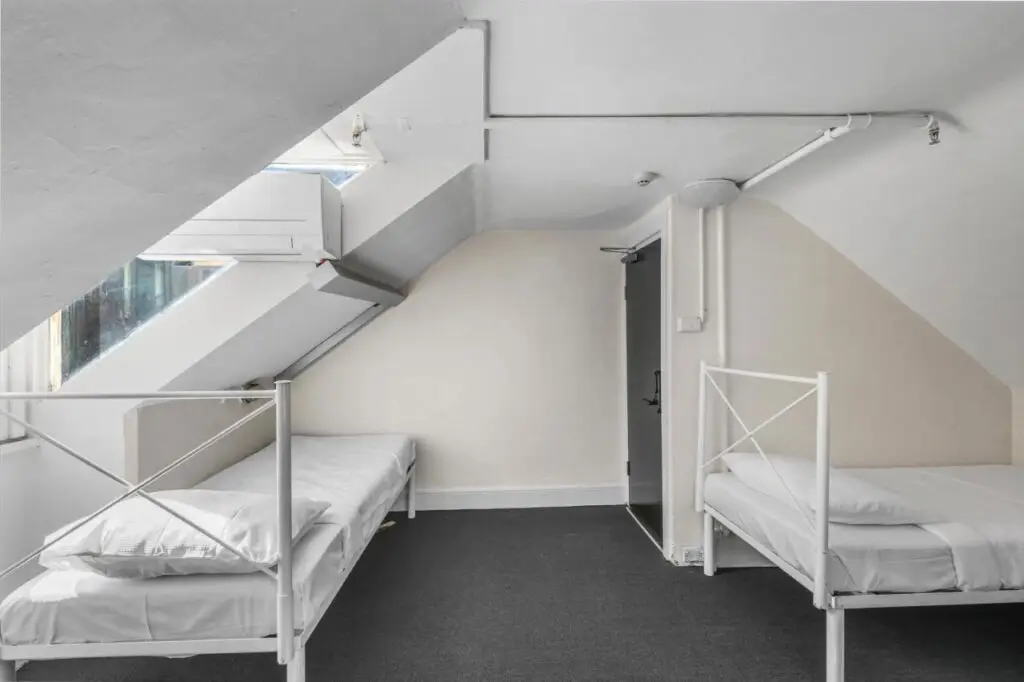 A three bed dormitory with clean white sheets for a relaxing stay at Urban Nomad Potts Point