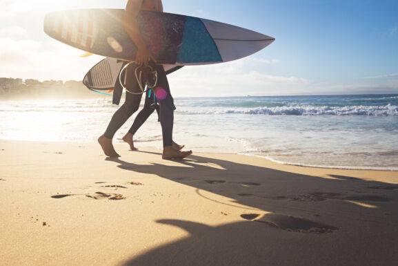 Australian surfers walking along Bondi Beach in the early morning for a surf. Bondi Beach New South Wales