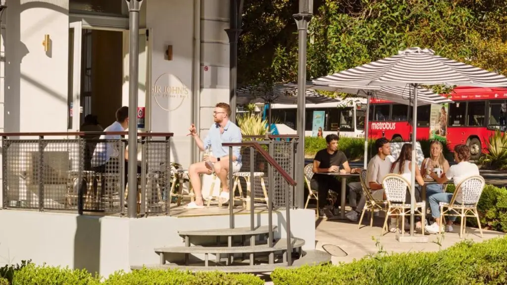 Cafe and outdoor space with people sitting at tables and chairs at The Pacific House.